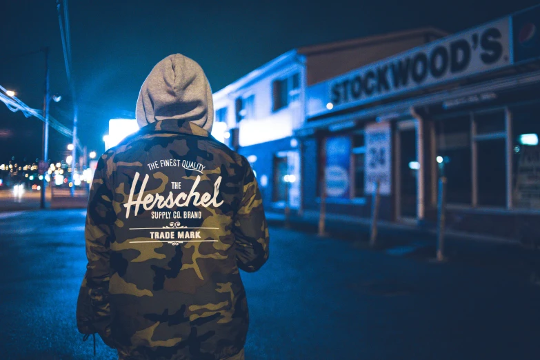 a man standing in the middle of a street at night, an album cover, inspired by Hendrick van Streeck, trending on unsplash, hyperrealism, wearing camo, she wears a jacket, normal rockwell, hollywood promotional image