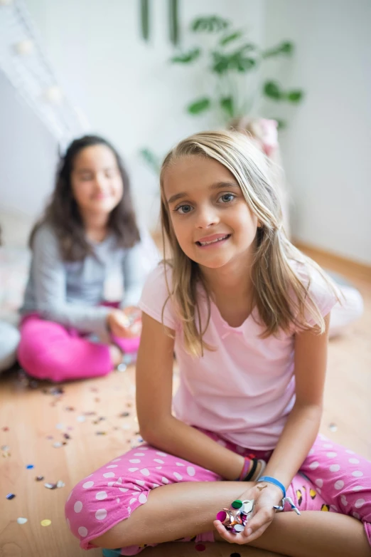 two girls sitting on the floor playing with confetti, by Lilia Alvarado, shutterstock, in the bedroom at a sleepover, looking towards camera, uncropped, good young girl