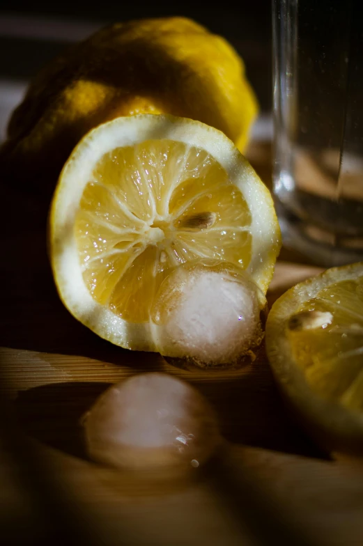 a slice of lemon next to a glass of water, a still life, pexels, icy, paul barson, a wooden, trimmed