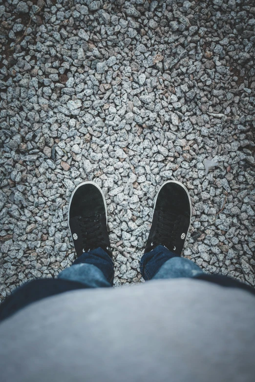 a person standing on top of a gravel covered ground, pexels contest winner, realism, black shoes, staring at you, low quality photo, wearing white sneakers
