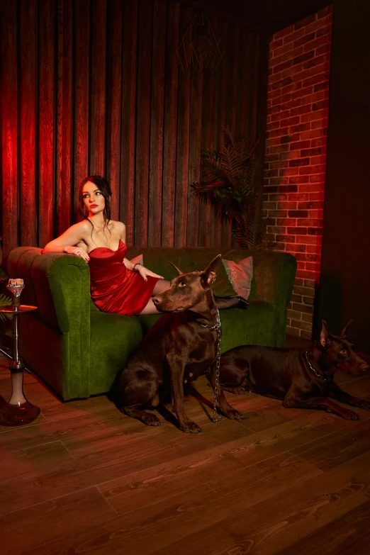 a woman sitting on a green couch next to a dog, by Winona Nelson, renaissance, cinematic red lighting, booze, studio photo, stoya