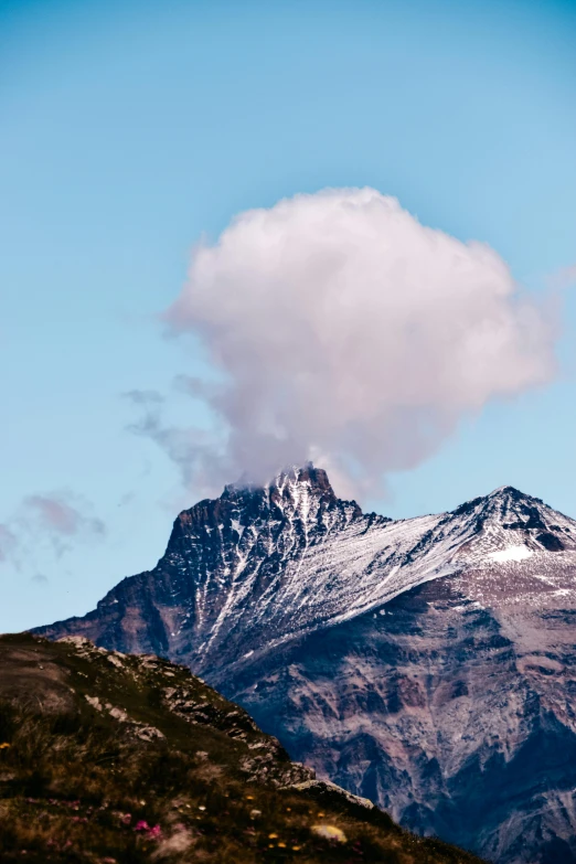 a mountain in the distance with a cloud in the sky, by Sven Erixson, trending on unsplash, patagonian, mushroom cloud, with snow on its peak, white hair floating in air