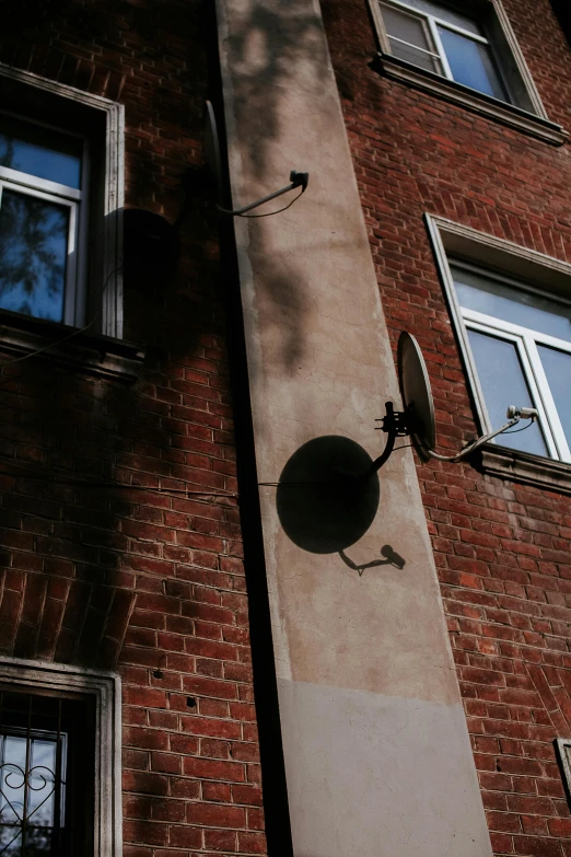 a satellite dish mounted to the side of a brick building, inspired by André Kertész, unsplash, spaghettification, low quality photo, in legnica, at home