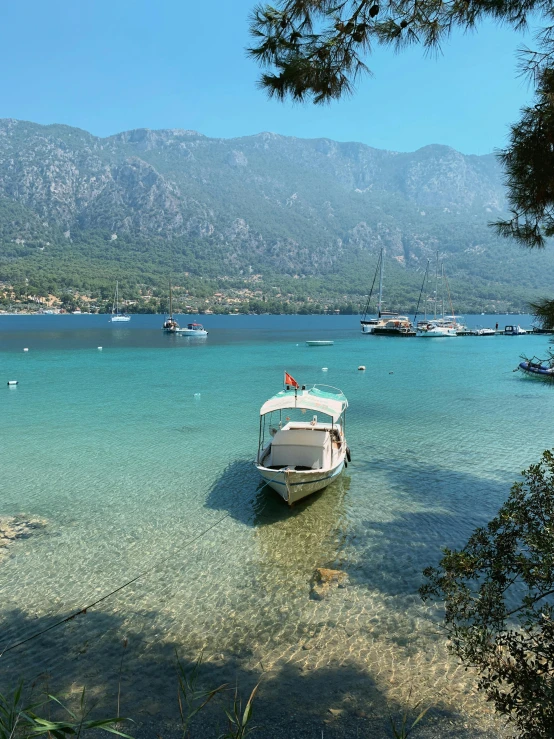 a boat that is sitting in the water, by Tom Wänerstrand, pexels contest winner, hurufiyya, slim aarons, lakeside mountains, crystal clear sea, thumbnail