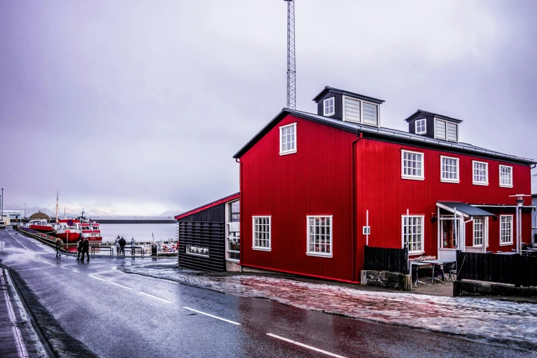 a red building sitting on the side of a road, by Roar Kjernstad, pexels contest winner, harbour, red white and black colors, red and obsidian neon, preserved historical