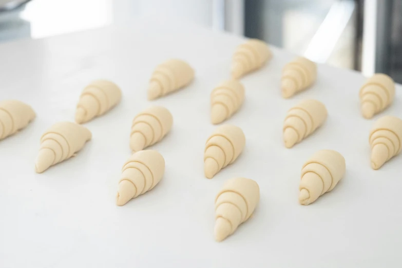 a table topped with lots of doughnuts on top of a counter, a marble sculpture, inspired by Louise Bourgeois, unsplash, white spiral horns, cone shaped, closeup - view, baking french baguette