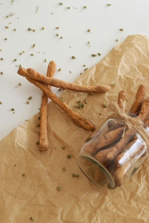 a jar filled with cinnamon sticks sitting on top of a piece of paper, by Emma Andijewska, cookies, hemp, italian, crackles