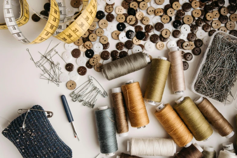 a table topped with lots of different types of thread, trending on pexels, flatlay, buttons, brown, designer product