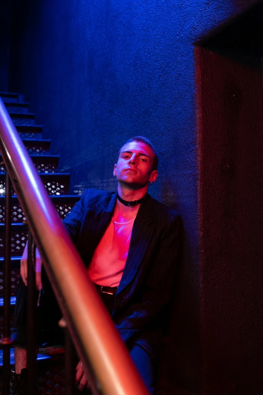 a man sitting on top of a set of stairs, an album cover, inspired by Elsa Bleda, unsplash, in a nightclub, smug look, bisexual lighting, bad bunny