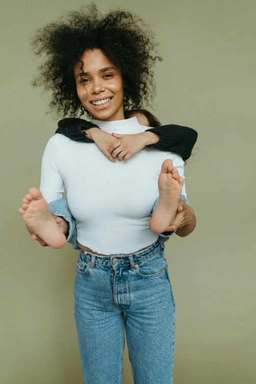 a woman holding a baby in her arms, an album cover, by Dulah Marie Evans, trending on pexels, jeans and t shirt, mixed race woman, happy toes, wearing turtleneck