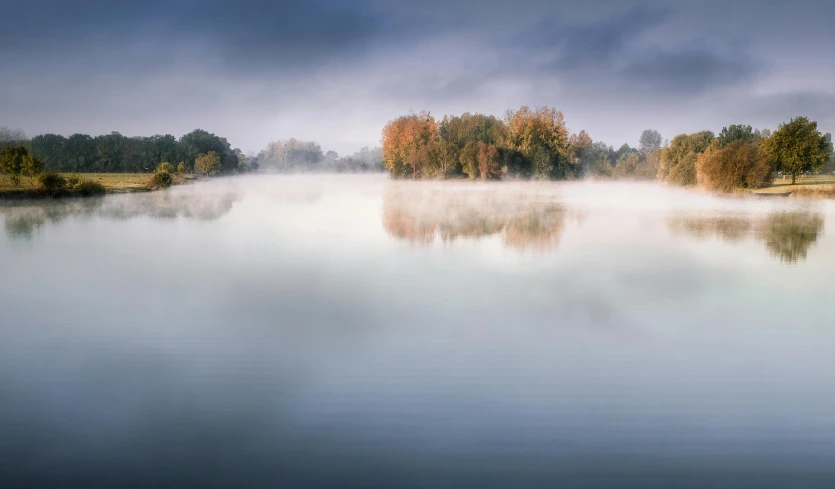 a body of water surrounded by trees on a foggy day, lpoty, outworldly colours, fine art print, ivan shishk