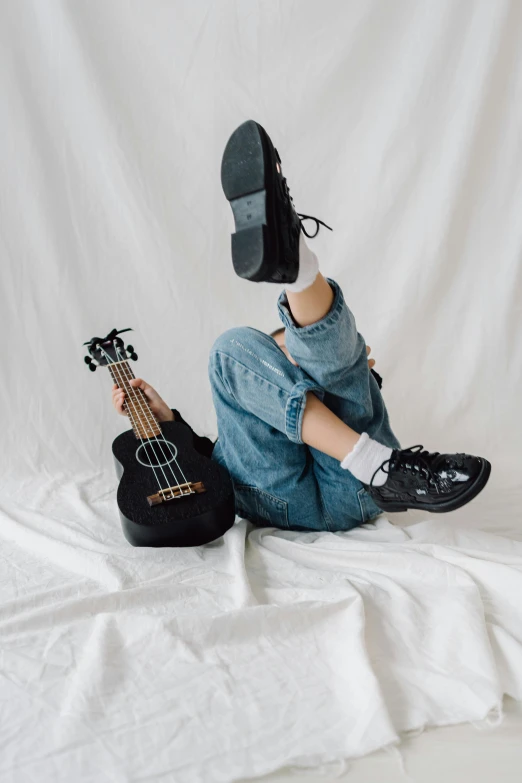 a person sitting on a bed with a guitar, by Everett Warner, unsplash contest winner, black loafers, on white background, sneaker photo, taejune kim