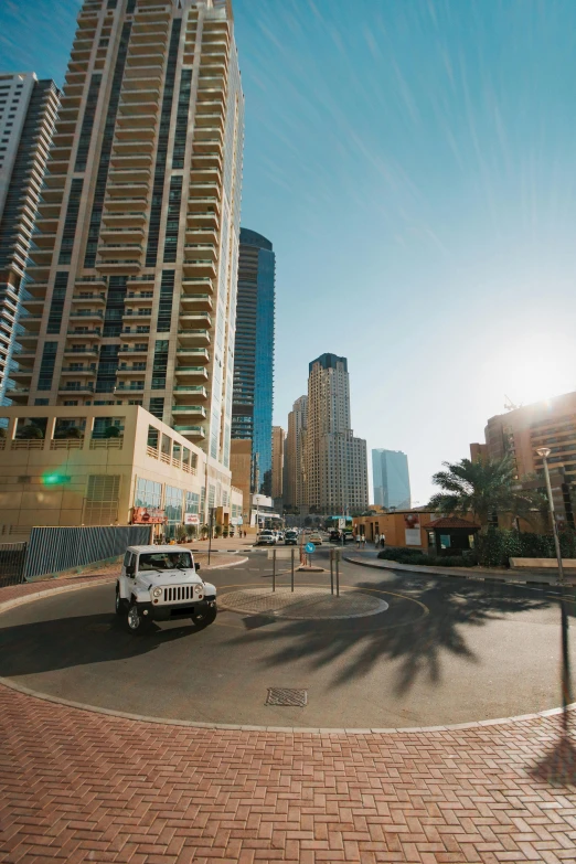 a car driving down a street next to tall buildings, dubai, 4k photo gigapixel, gold coast australia, sun flares