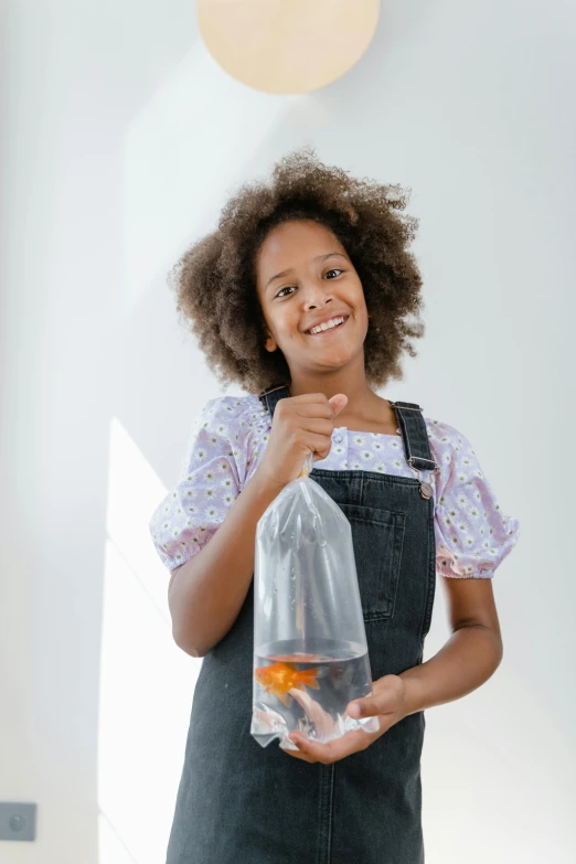 a woman holding a bag with a fish inside of it, pexels contest winner, renaissance, black teenage girl, bottle, fish tank, girl standing