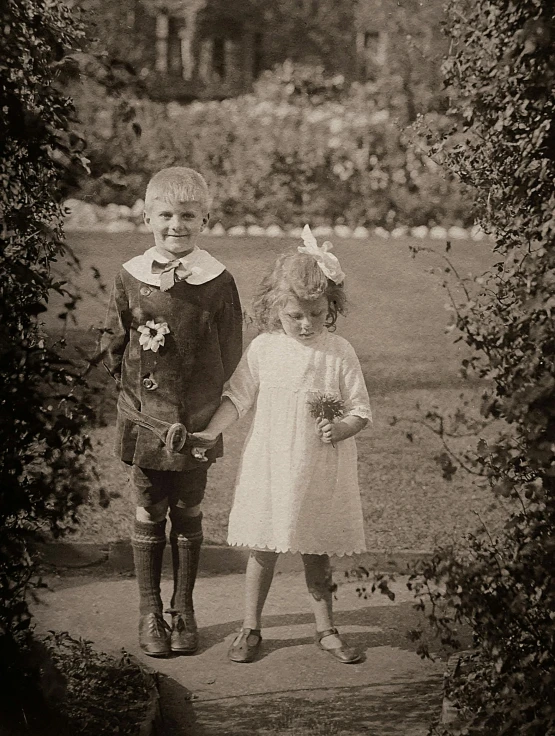 a couple of kids standing next to each other, a black and white photo, by Phyllis Ginger, renaissance, in a garden, sepia toned, slide show, 1 9 2 0 s style