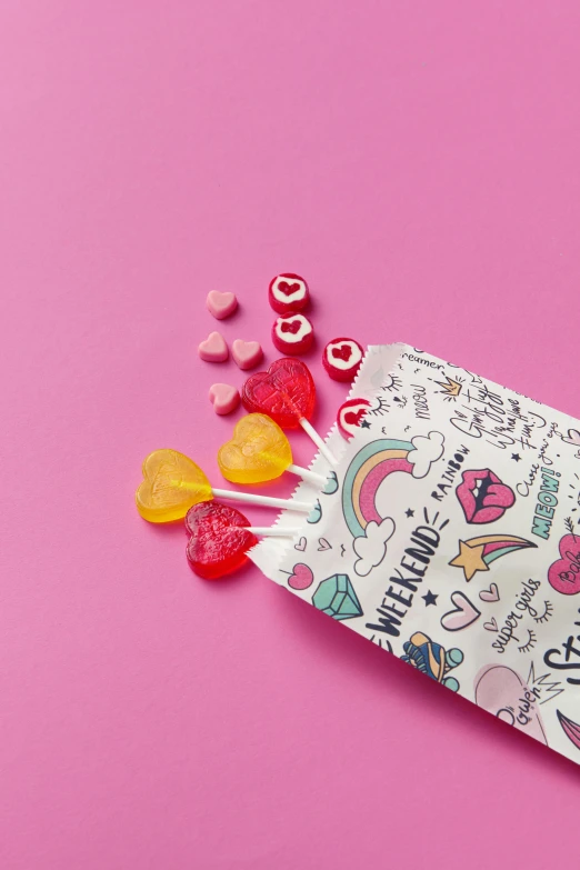a bag of candy sitting on top of a pink surface, hearts, rainbow coloured rockets, graphic print, lifestyle