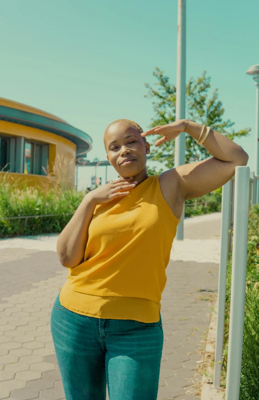 a woman standing in front of a street sign, an album cover, by Lee Gatch, pexels, wearing yellow croptop, bald head, battle pose, official music video