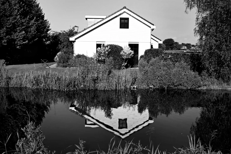 a white house sitting next to a body of water, a black and white photo, by Jan Pynas, pixabay, op art, wet reflections in square eyes, in a garden of a house, dutch landscape, taken on 1970s kodak camera