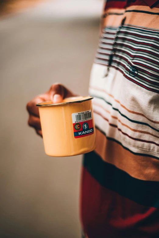 a close up of a person holding a cup, by Daniel Seghers, labels, kodak color, campy and colorful, caramel. rugged