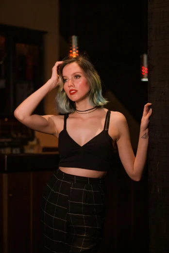 a woman in a black top and plaid pants, inspired by Elsa Bleda, featured on reddit, at a bar, aurora aksnes, halter top, headshot photo