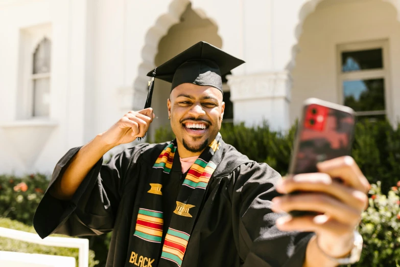 a man in a graduation cap and gown taking a selfie, unsplash, african aaron paul, black robes, delightful surroundings, student