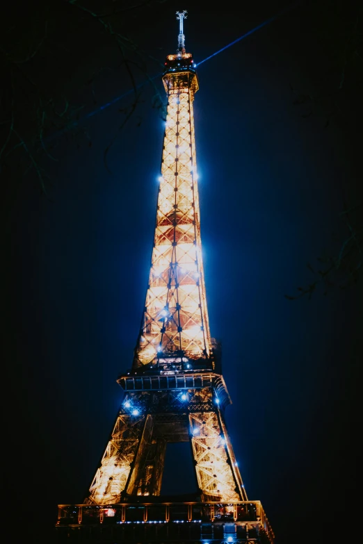 the eiffel tower is lit up at night, a photo, unsplash contest winner, 3/4 view from below, color”