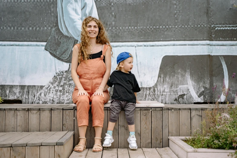 a woman and a child sitting on a bench, a portrait, graffiti, wearing overalls, nina tryggvadottir, architect, thumbnail