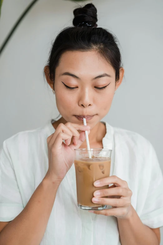 a woman drinking a glass of iced coffee, inspired by Ruth Jên, smoothed lip line, longque chen, with a straw, manuka