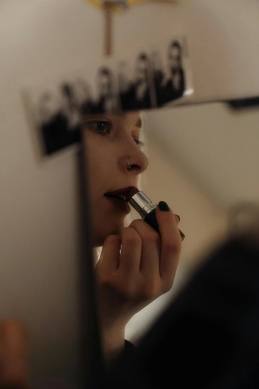 a woman putting on lipstick in front of a mirror, inspired by Nan Goldin, reddit, photorealism, makeup. unreal engine, color footage, dark lipstick, a high angle shot
