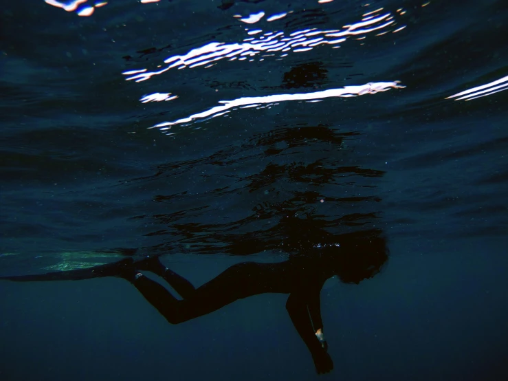 a person in the water with a surfboard, by Maggie Hamilton, unsplash, a dark underwater scene, still from the film, rinko kawauchi, unconscious