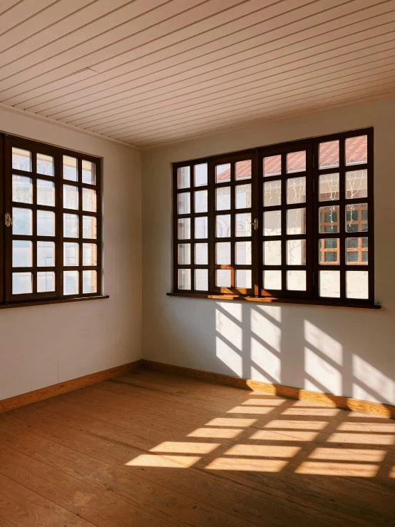 an empty room with wooden floors and windows, inspired by Donald Judd, unsplash, sunny bay window, light breaks through the roofs, changquan, an escape room in a small