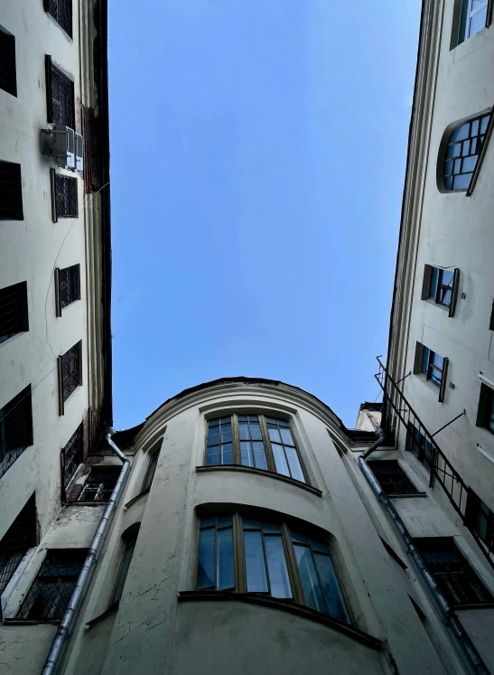 a couple of tall buildings next to each other, an album cover, unsplash, neoclassicism, post - soviet courtyard, worm\'s eye view, neo kyiv, alleys