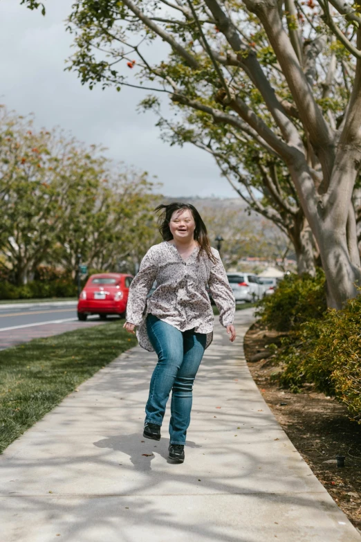 a woman walking down a sidewalk next to trees, inspired by helen huang, happening, flying towards the camera, wearing a shirt and a jean, oceanside, bbwchan