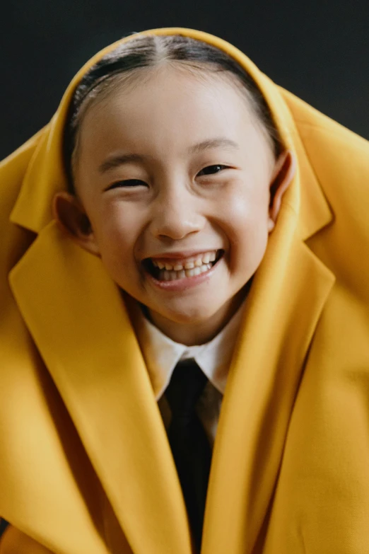 a young boy wearing a yellow coat and a black tie, inspired by Chen Daofu, pexels contest winner, gutai group, smiling girl, slide show, hood and cape, closeup shot