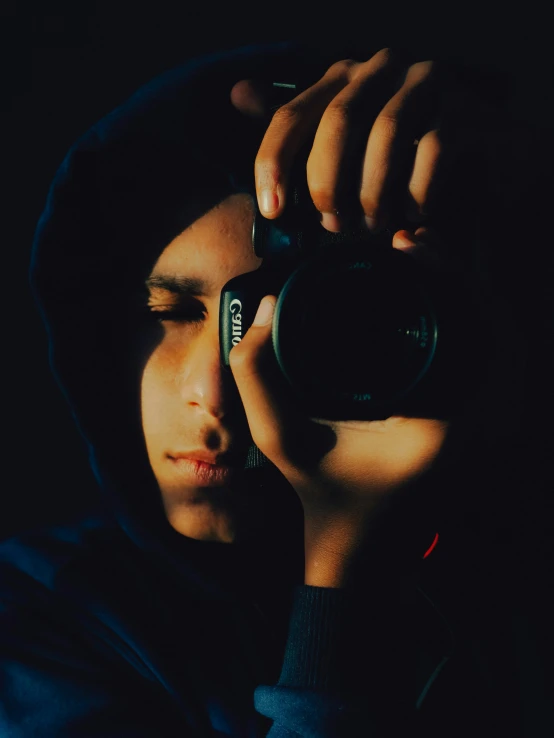 a person taking a picture with a camera, wearing a dark hood, ((portrait)), super focused, ((sharp focus))