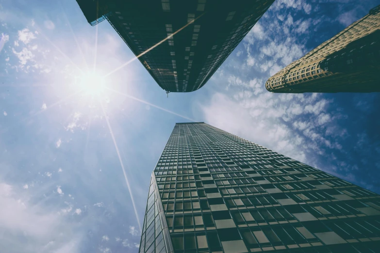 a group of tall buildings sitting next to each other, by Adam Rex, pexels contest winner, solarised, looking up onto the sky, thumbnail, three towers