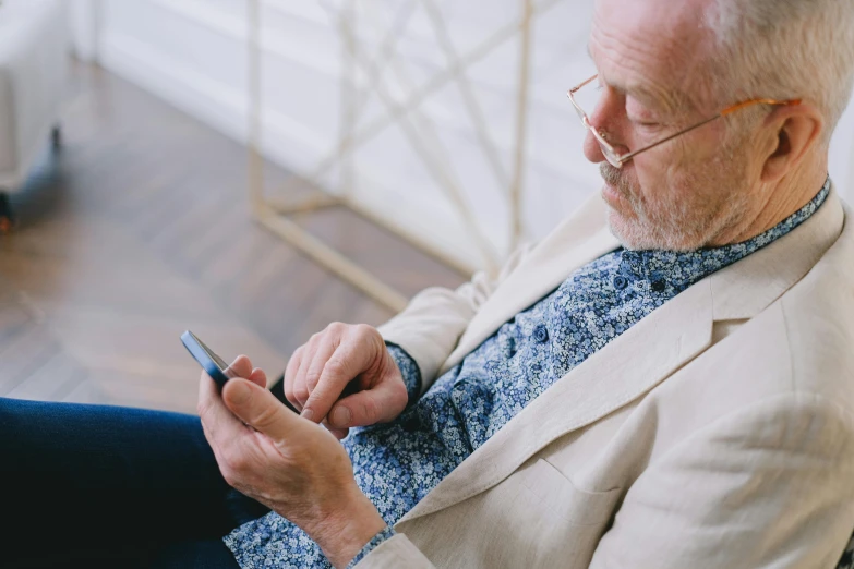 a man sitting in a chair using a cell phone, profile image, grandfatherly, portrait featured on unsplash, digital medical equipment