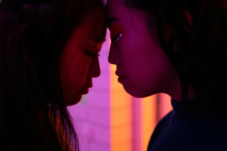 a couple of women standing next to each other, inspired by Nan Goldin, trending on pexels, realism, 8 0 s asian neon movie still, red and purple, facing each other, movie scene close up