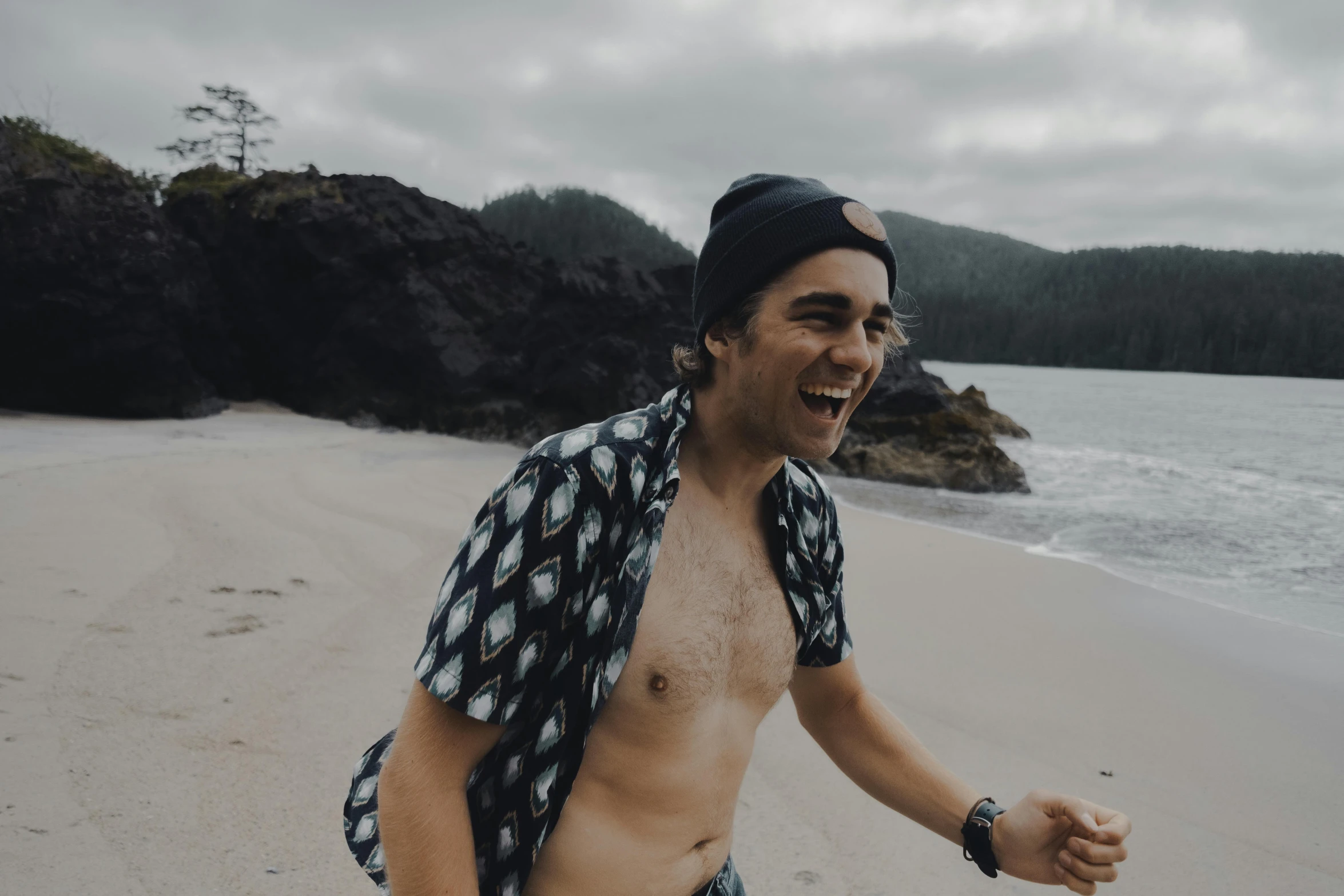 a man standing on top of a beach next to a body of water, by Adam Dario Keel, happening, smiling laughing, haida gwaii, avatar image, ben askren