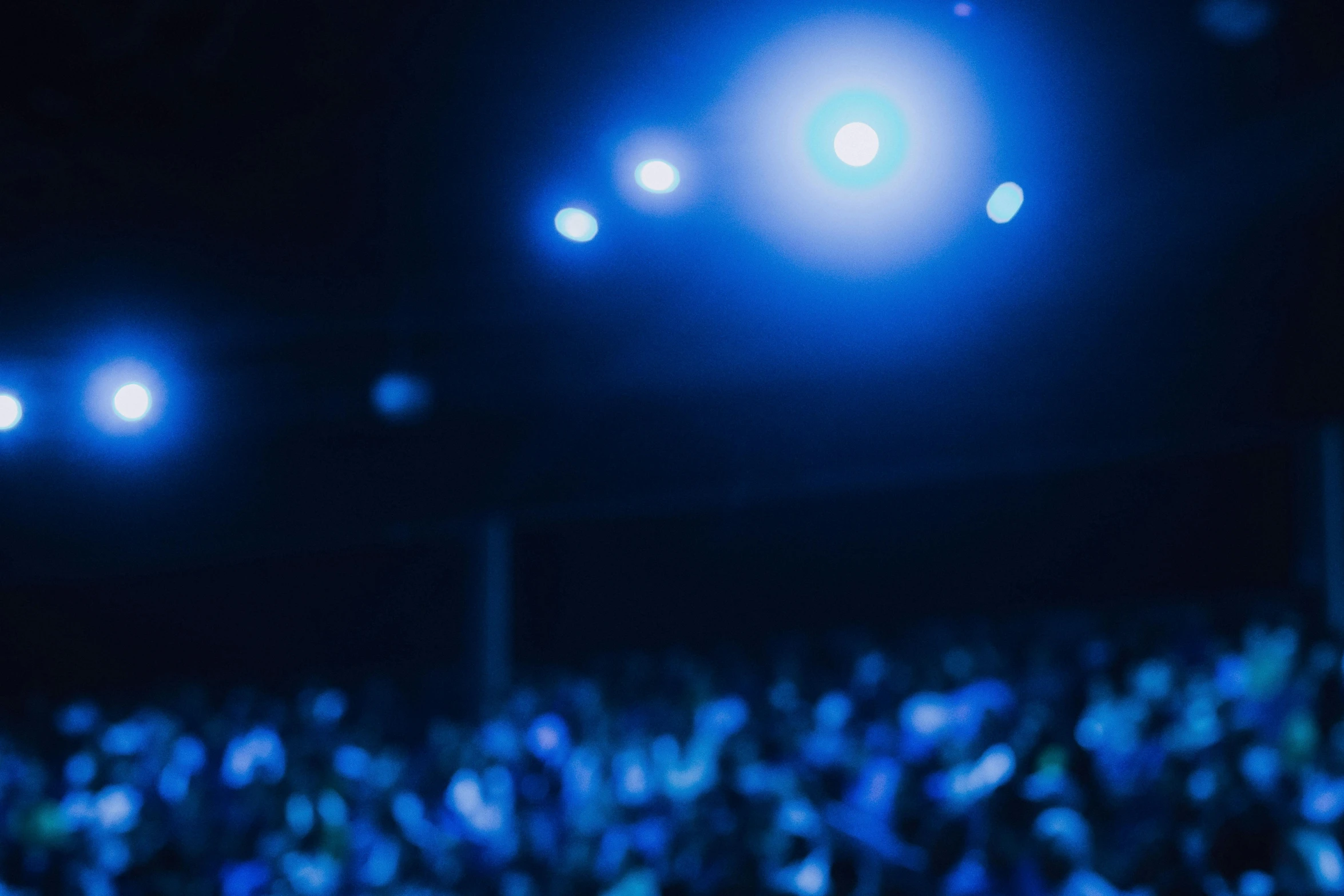 a large group of people standing in front of a stage, pexels contest winner, happening, blue blurred, dark. no text, blue bioluminescent plastics, people watching