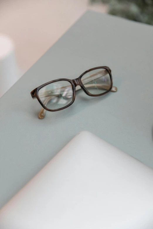 a pair of glasses sitting on top of a laptop computer, brown resin, vanilla, detail shot, square glasses