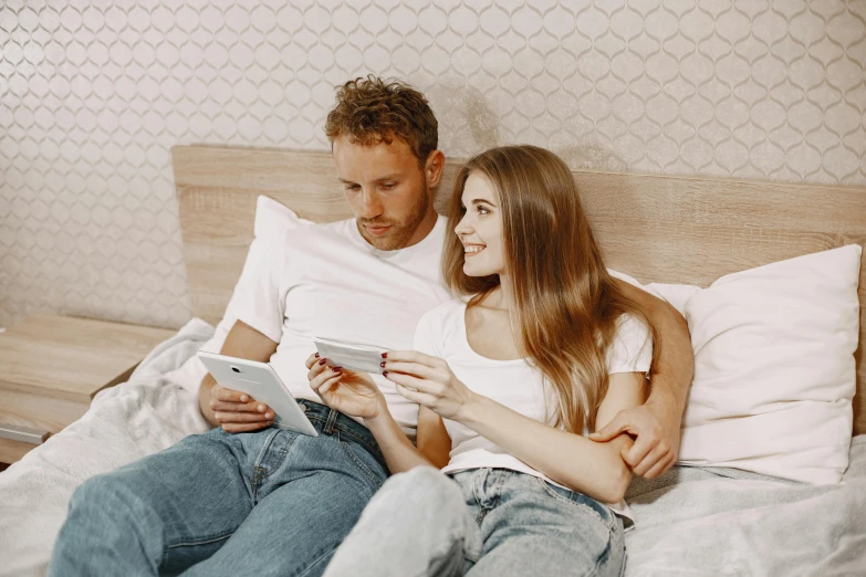 a man and woman sitting on a bed looking at a tablet, trending on pexels, russian girlfriend, avatar image, casey cooke, profile image