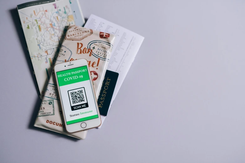 a cell phone sitting on top of a pile of papers, by Carey Morris, pexels contest winner, smartphone displays qr code, passport, green colored theme, covid