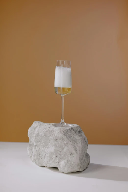 a glass of wine sitting on top of a rock, a marble sculpture, white foam, but minimalist, super long shot, bubbly