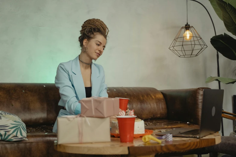 a woman sitting on a couch with a bunch of presents, pexels contest winner, happening, sitting on a mocha-colored table, cinematic footage, girl with messy bun hairstyle, people at work