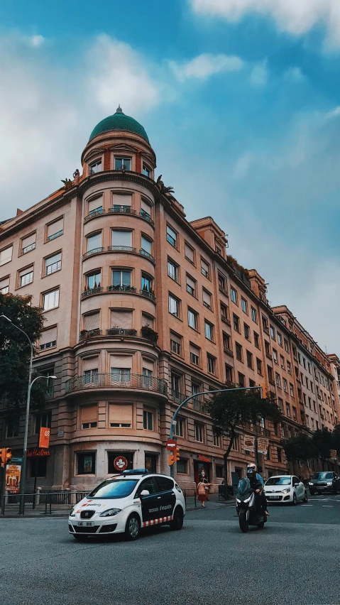 a group of cars driving down a street next to tall buildings, by Matija Jama, pexels contest winner, art nouveau, freddy mamani silvestre facade, spanish, 2 5 6 x 2 5 6 pixels, huge mansion