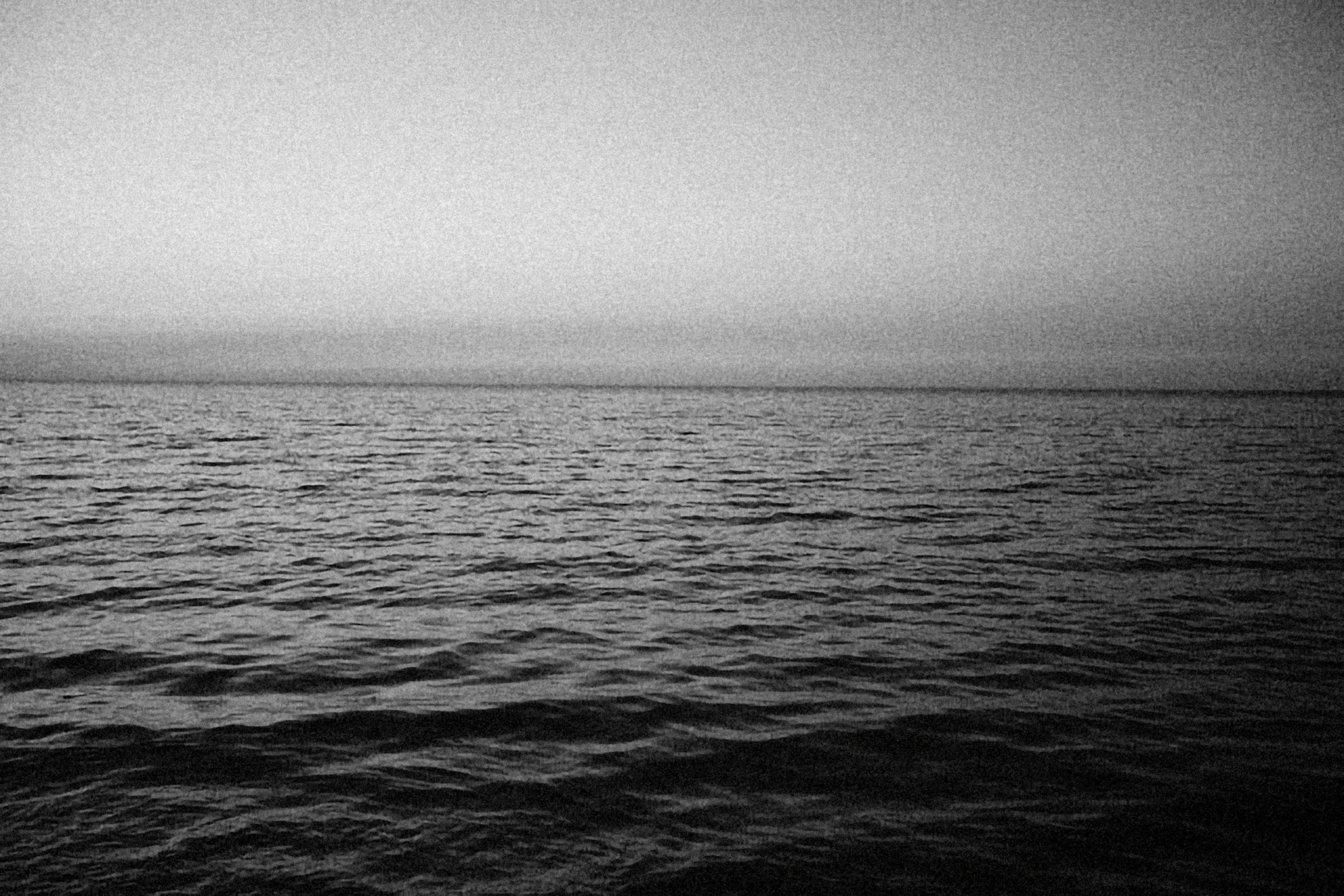 a black and white photo of the ocean, a black and white photo, pexels, minimalism, 2 5 6 x 2 5 6 pixels, calm evening, red sea, far - mid shot