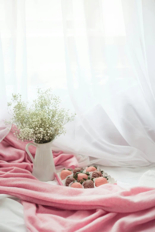 a white vase sitting on top of a bed next to a pink blanket, a still life, by Basuki Abdullah, unsplash, romanticism, strawberries, candy pastel, ethereal curtain, bouquets