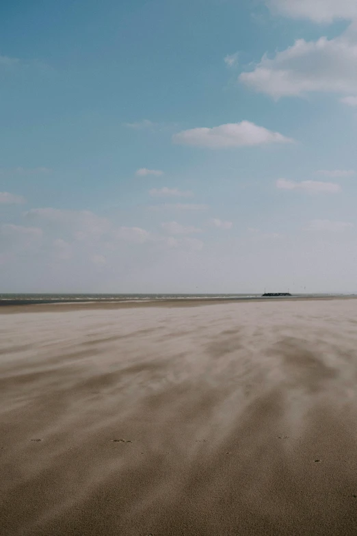 a man flying a kite on top of a sandy beach, by Jan Nieuwenhuys, unsplash, land art, wide panoramic shot, very sparse detail, video, dunkirk