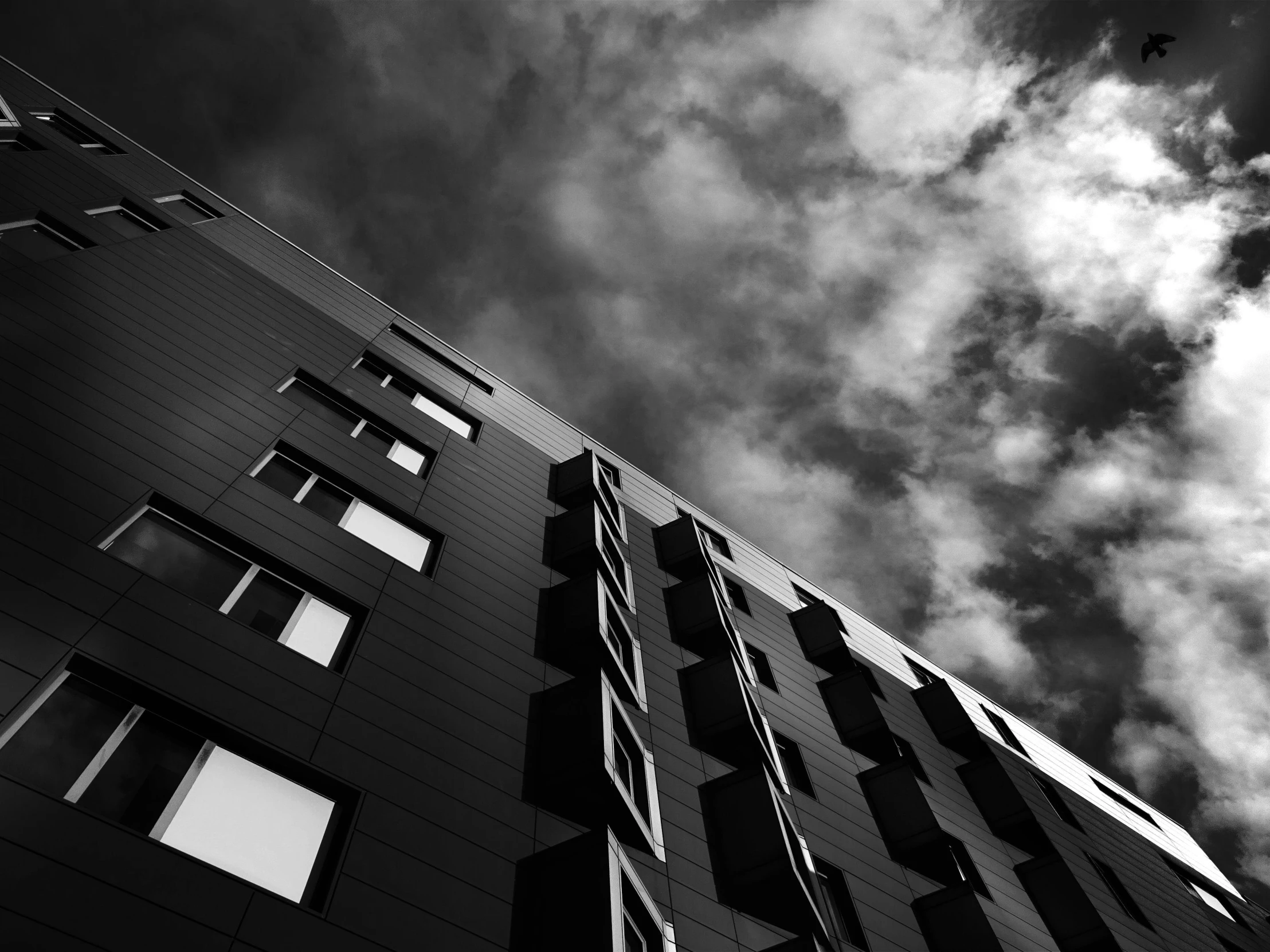 a black and white photo of a tall building, by Matthias Weischer, unsplash, dark clouds above, ten flats, square, taken with my nikon d 3